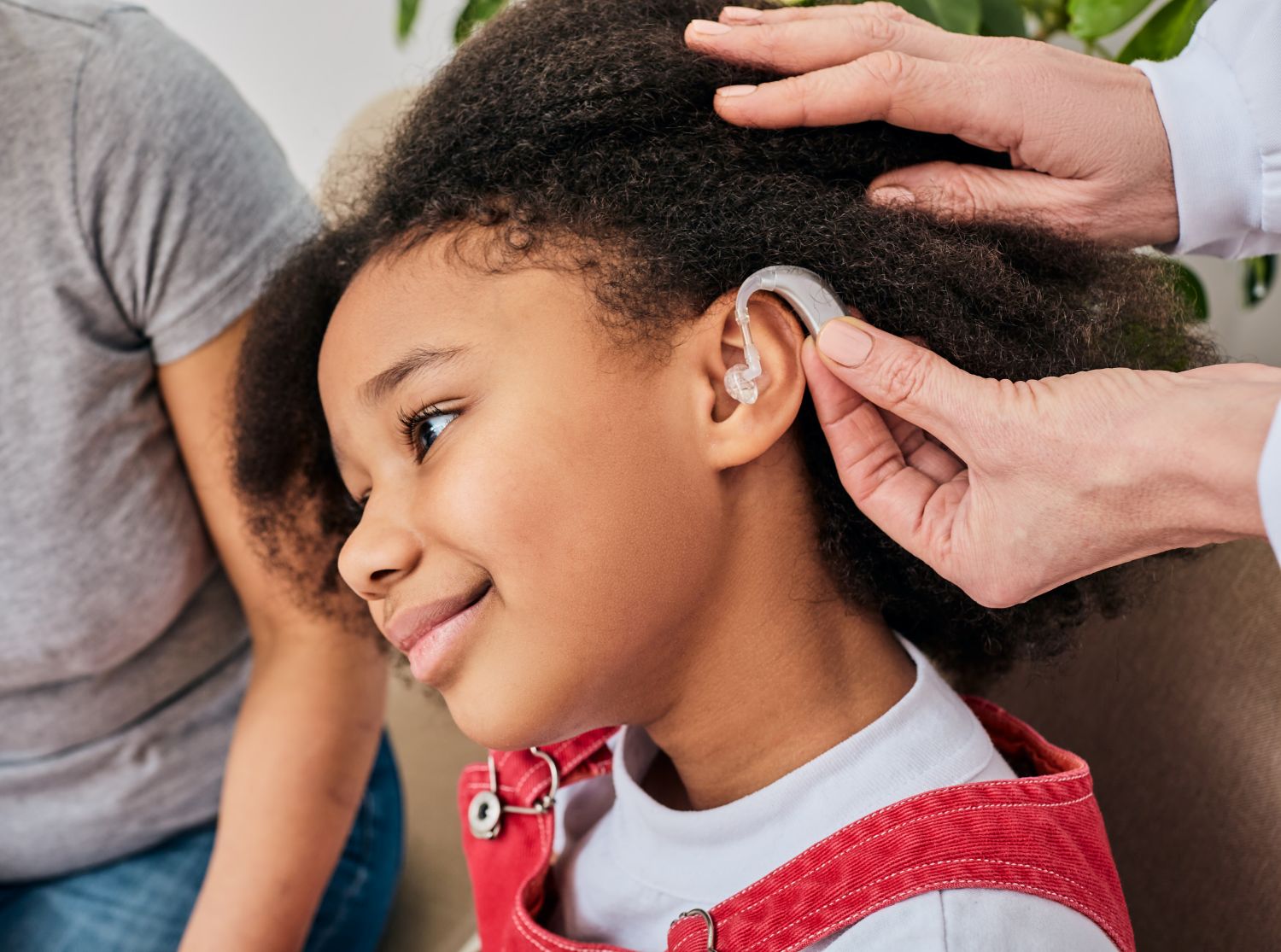 doctor installing a hearing aid on little girl